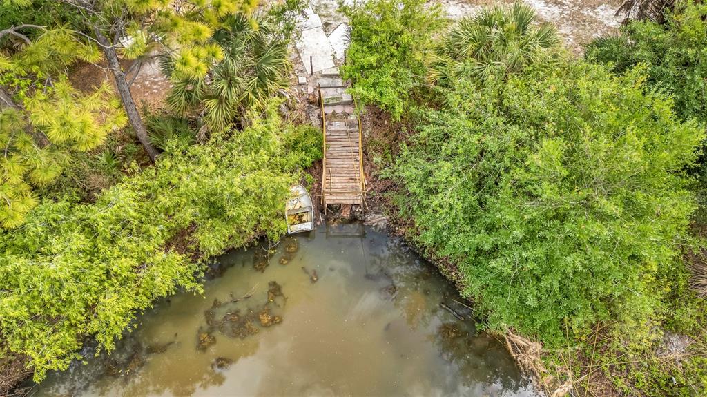 An aerial view shows a wooden dock and a small boat in a murky pond — 24789 NOVA LANE, PUNTA GORDA, FL