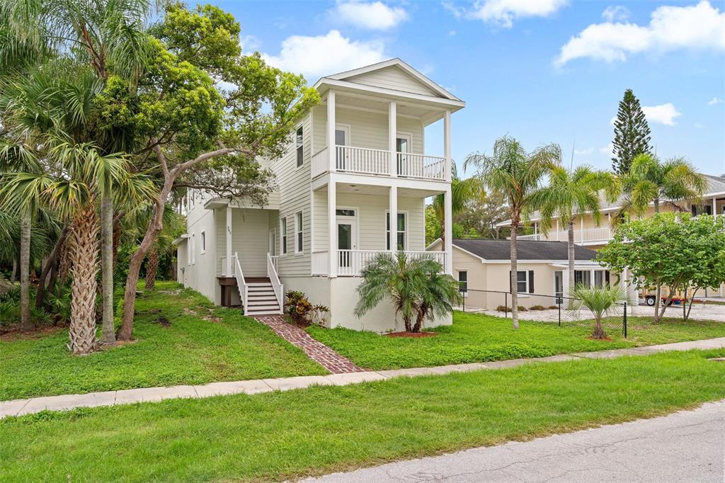A two-story light green house with double-stacked porches and a brick walkway — 385 GEORGIA AVENUE, CRYSTAL BEACH, FL