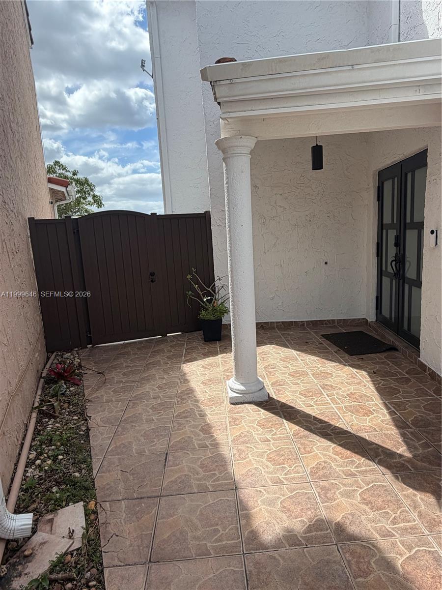 A tiled entryway features a white column, a dark gate, and a glass-paneled front door — 13267 SW 9th Ln, Miami FL 33184, MIAMI, FL