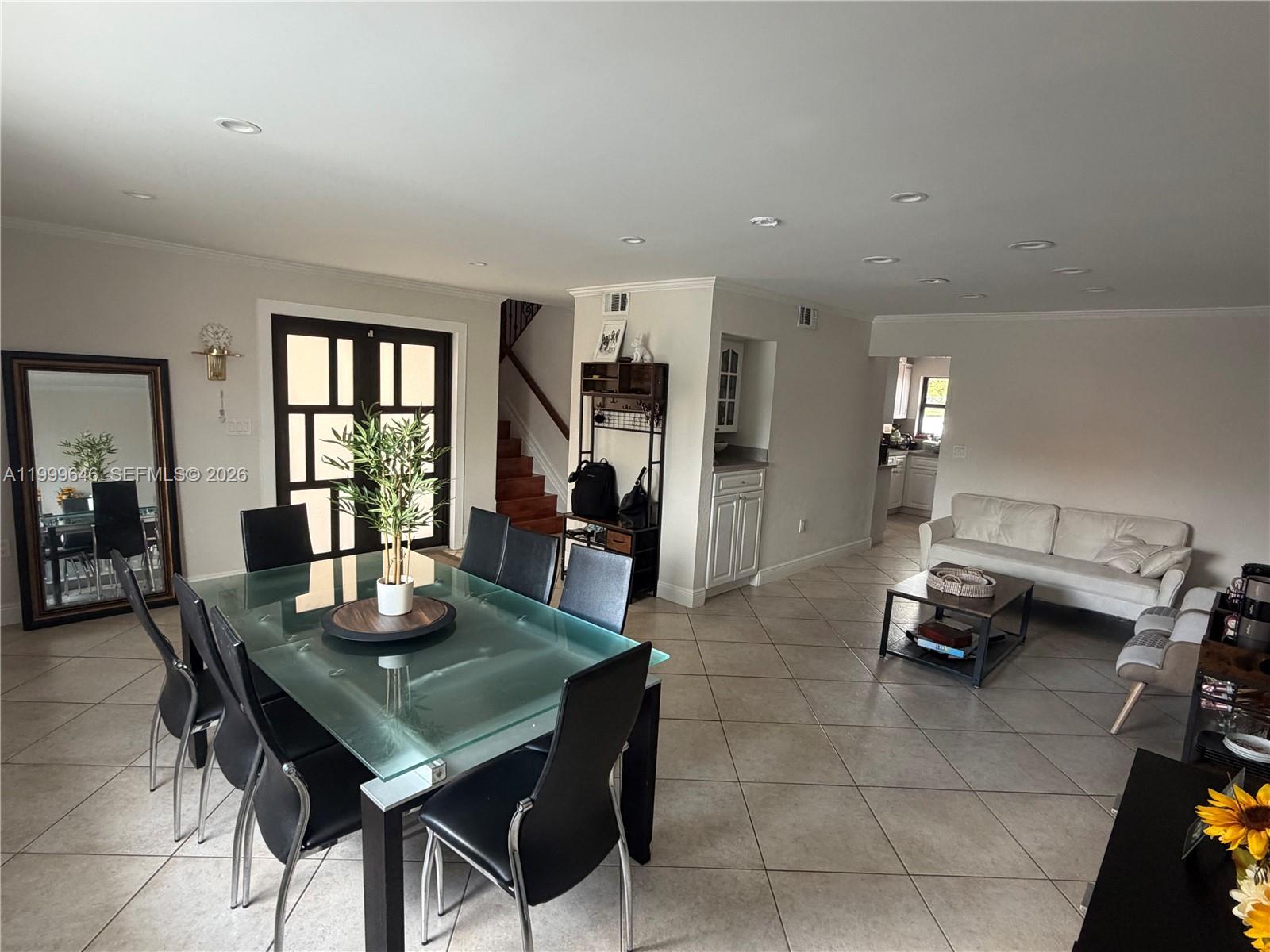 A dining area with a glass table and black chairs opens into a living room — 13267 SW 9th Ln, Miami FL 33184, MIAMI, FL
