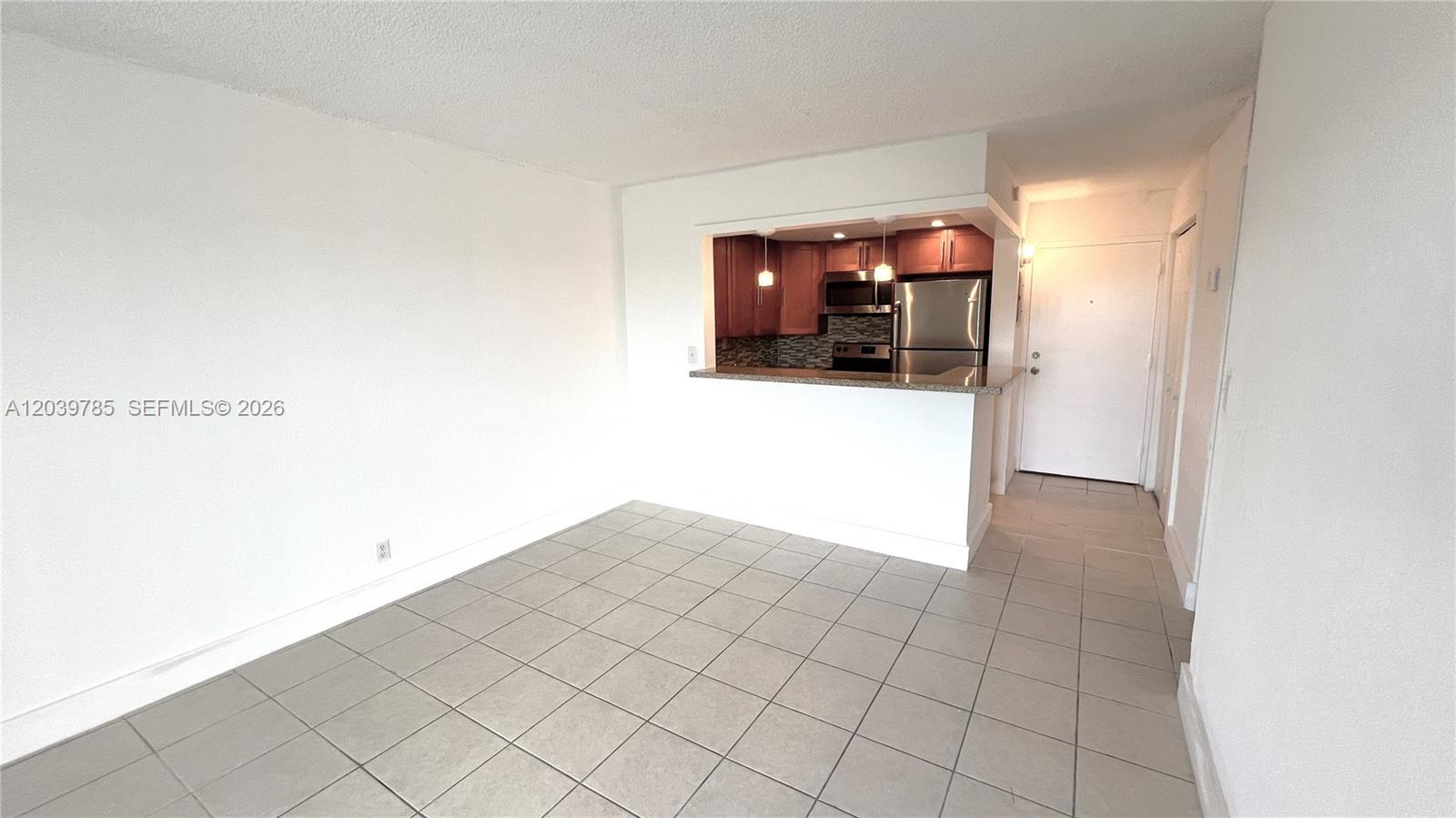 A tiled dining area features a pass-through window looking into a kitchen with cabinets — 4550 NW 9th St # 516E, Miami FL 33126, MIAMI, FL