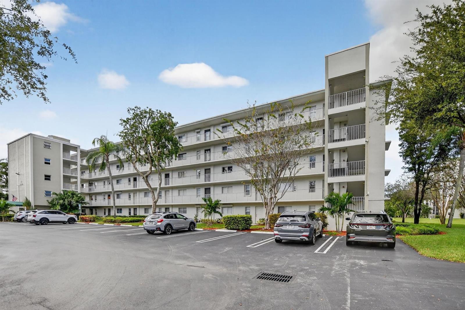A multi-story apartment building with a parking lot in front under a cloudy sky — 2236 N Cypress Bend Drive # 508, Pompano Beach FL 33069, POMPANO BEACH, FL