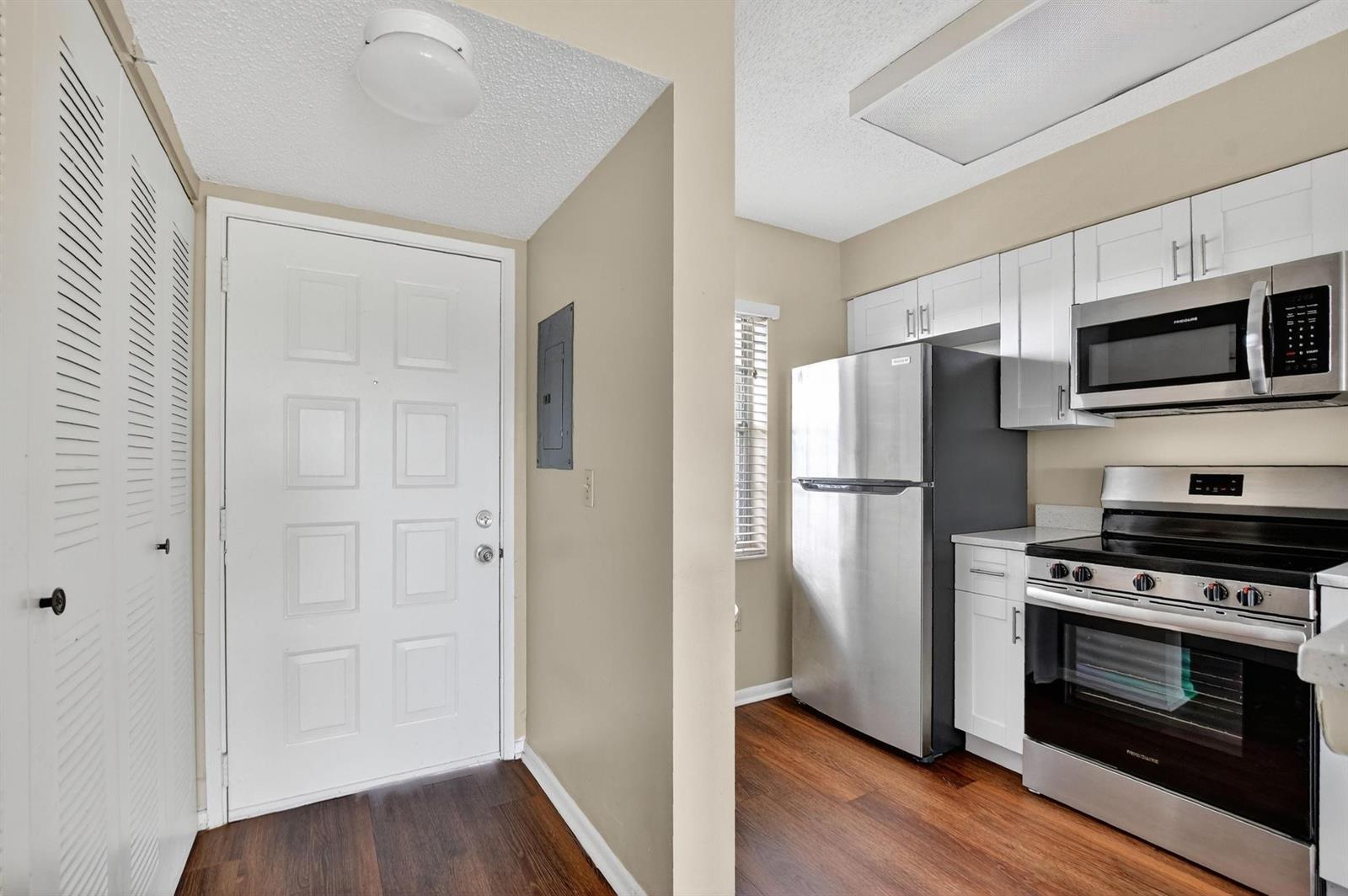 A view of an entryway with a white door and a small adjacent kitchen area — 2236 N Cypress Bend Drive # 508, Pompano Beach FL 33069, POMPANO BEACH, FL