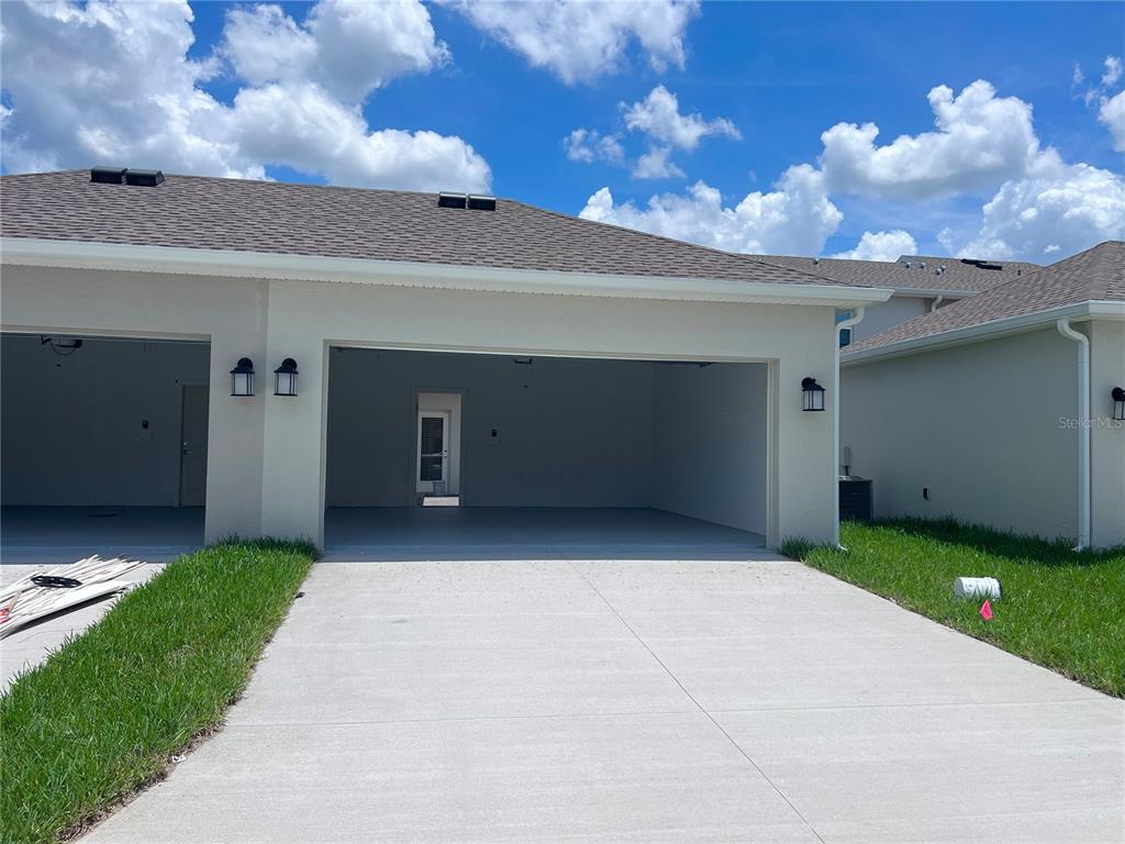 A view of a concrete driveway leading to an open two-car garage — 10534 TRIBUTE DRIVE, WINTER GARDEN, FL