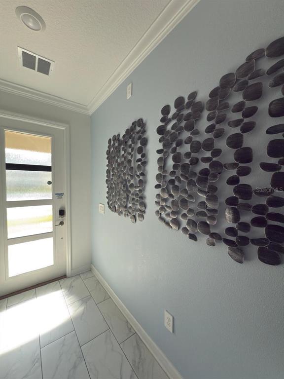 An entryway features light blue walls, marble-look tile flooring, and two large metal wall sculptures — 1173 KINGSBARN STREET, DAVENPORT, FL