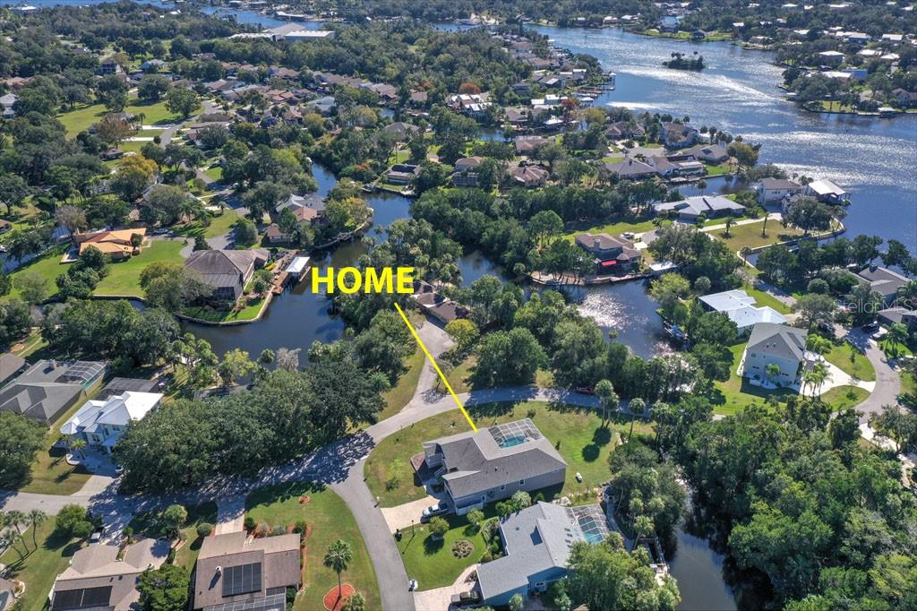 An aerial view shows a residential house with a pool and a canal-front backyard — 11752 W VALLEY SPRING LANE, HOMOSASSA, FL