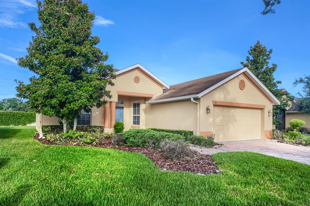 A single-story house with a tan stucco exterior, a two-car garage, and a large tree — 380 SORRENTO ROAD, KISSIMMEE, FL