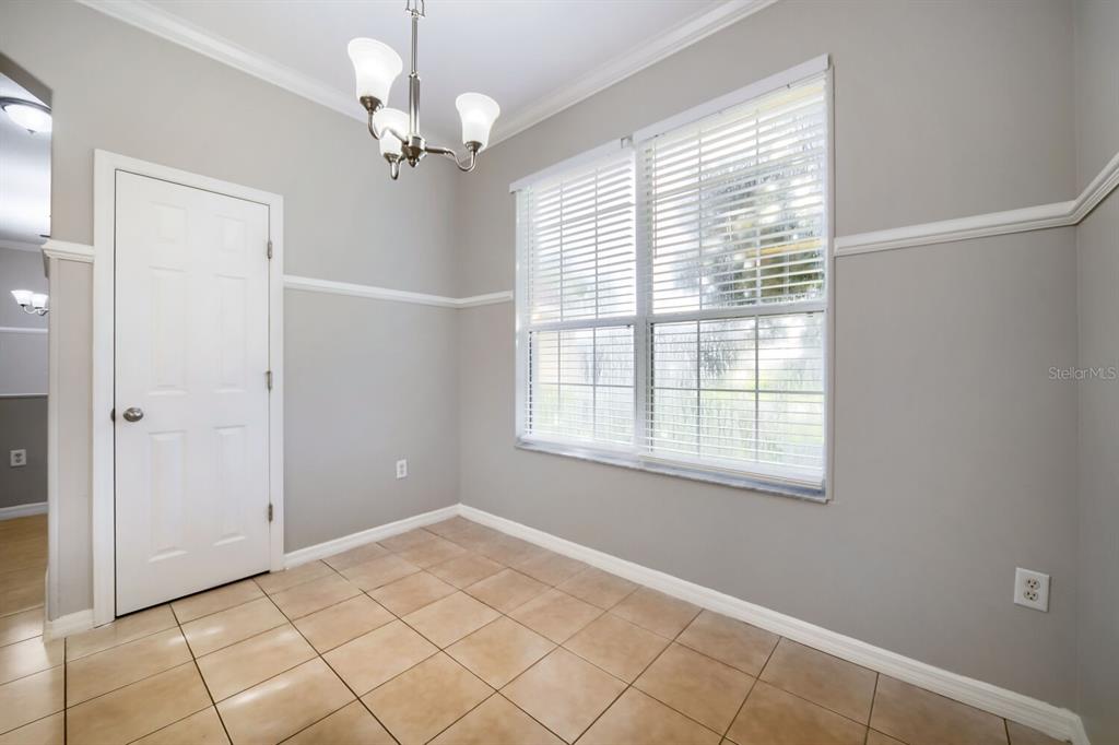 A dining area features light gray walls, tile flooring, a chandelier, and a large window — 380 SORRENTO ROAD, KISSIMMEE, FL