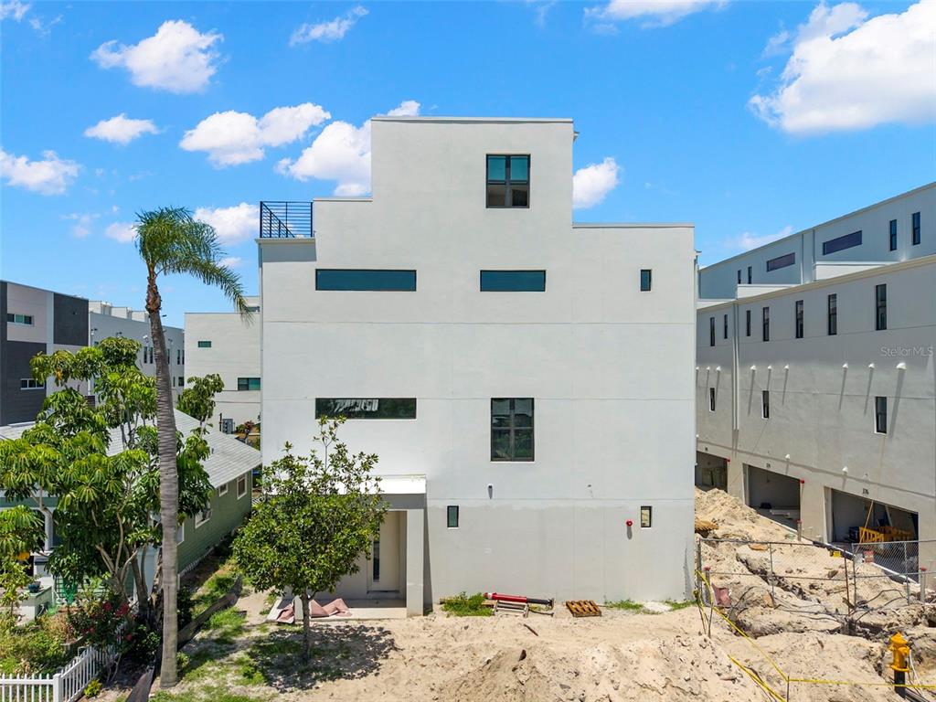 A modern white multi-story house stands next to a construction site under a blue sky — 368 14TH STREET N, ST PETERSBURG, FL