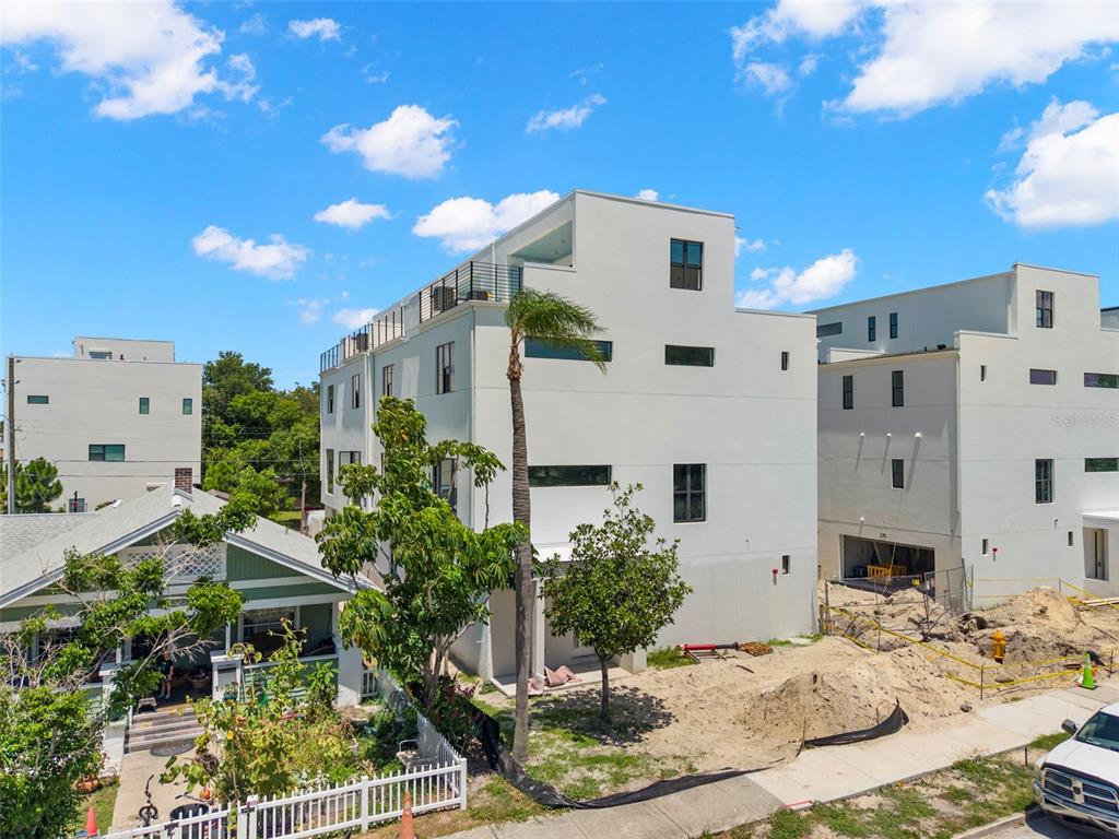 A modern multi-story white building stands next to a smaller house and a construction site — 368 14TH STREET N, ST PETERSBURG, FL