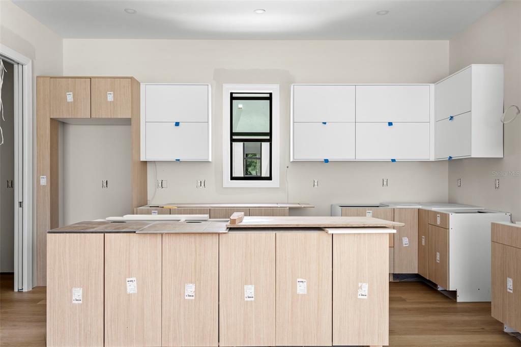 An unfinished kitchen features light wood-toned cabinetry, white upper cabinets, and a central island — 368 14TH STREET N, ST PETERSBURG, FL