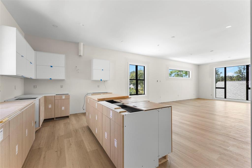 An unfinished kitchen features light wood cabinetry, a central island, and large windows in an open-concept space — 368 14TH STREET N, ST PETERSBURG, FL