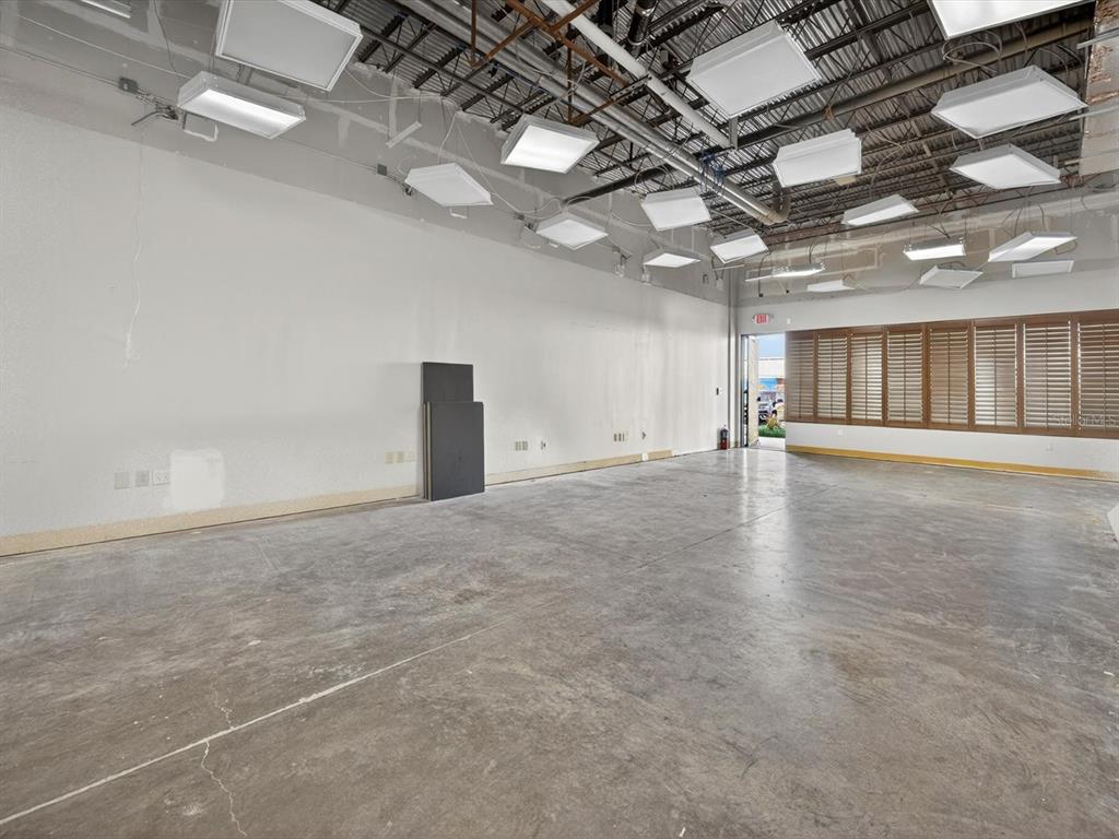 An empty commercial space features a concrete floor, white walls, and an exposed industrial ceiling — 250 AVENUE K SW UNIT 104, WINTER HAVEN, FL