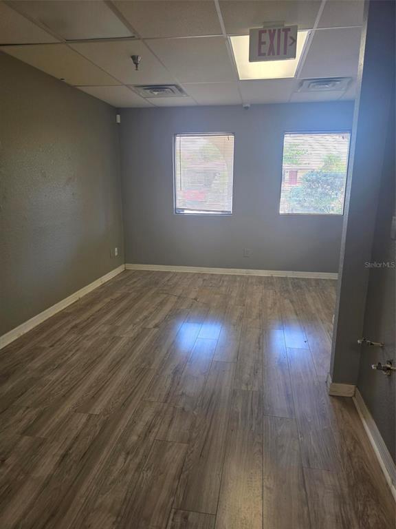 An empty office room features gray walls, wood-look flooring, and two windows with blinds — 4120 TAMIAMI TRAIL UNIT D1, PORT CHARLOTTE, FL