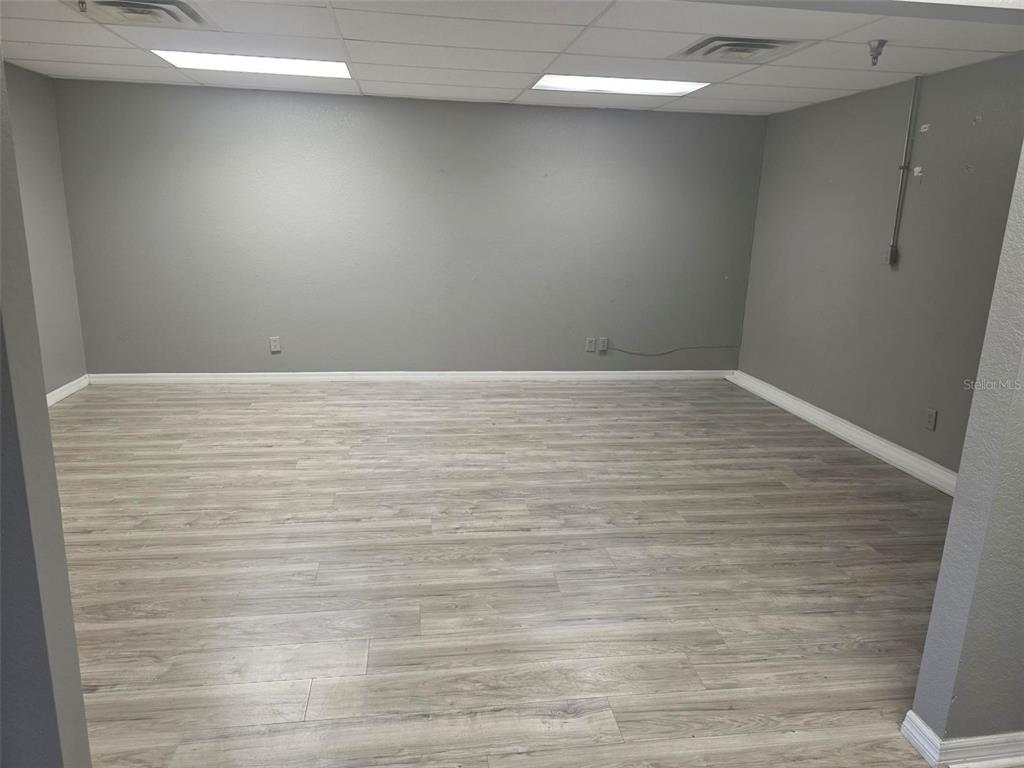 An empty room features gray walls, light wood-look flooring, and a drop ceiling with lights — 4120 TAMIAMI TRAIL UNIT D1, PORT CHARLOTTE, FL