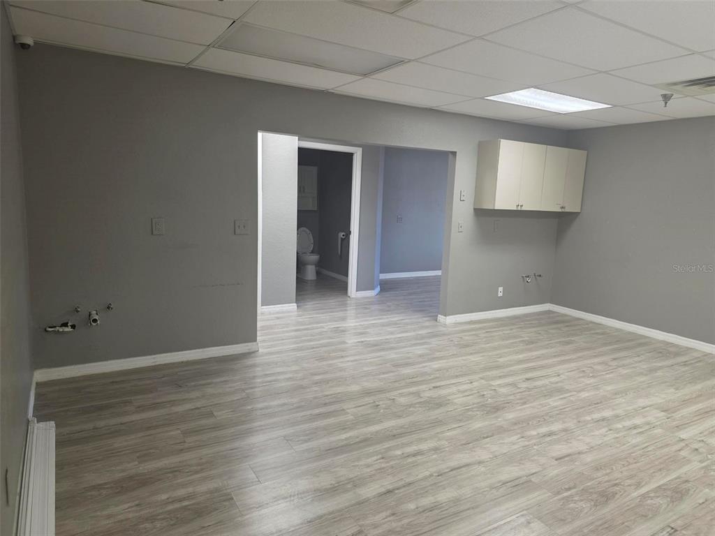An interior room features gray walls, light wood-look flooring, a drop ceiling, and a bathroom — 4120 TAMIAMI TRAIL UNIT D1, PORT CHARLOTTE, FL