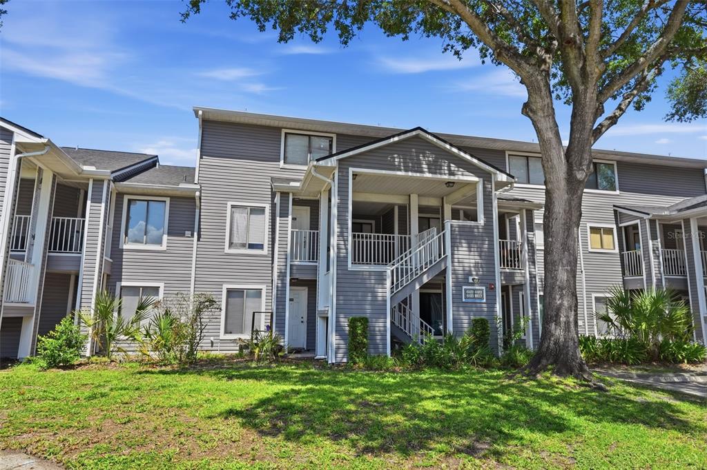 A multi-story apartment building with gray siding, white trim, and an exterior staircase — 2216 STONINGTON AVENUE UNIT 2216, ORLANDO, FL