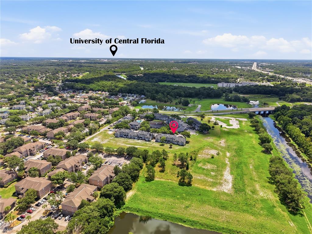 An aerial view shows a residential apartment complex surrounded by green space and a river — 2216 STONINGTON AVENUE UNIT 2216, ORLANDO, FL