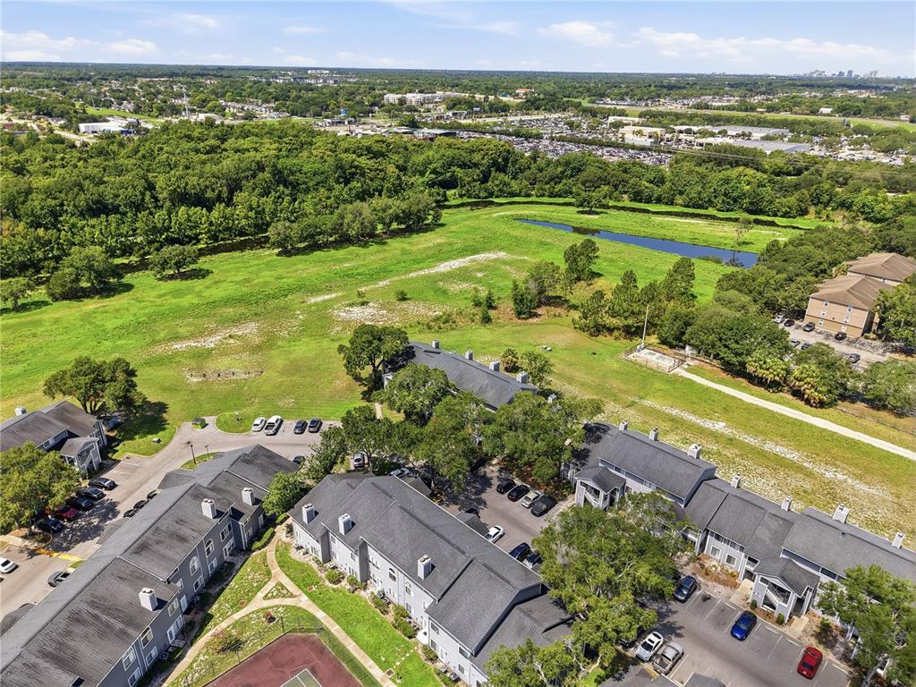 An aerial view shows multi-story apartment buildings with gray roofs surrounded by green space — 2216 STONINGTON AVENUE UNIT 2216, ORLANDO, FL