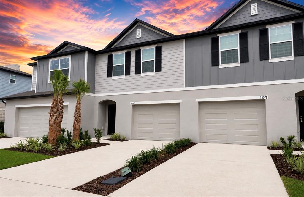A multi-unit residential building with gray siding, stucco lower walls, and three garage doors — 32079 EASTERN REDBUD BRANCH, SAN ANTONIO, FL