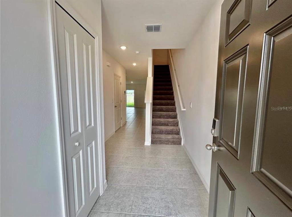 An entryway features a tiled floor, a carpeted staircase, and a white closet door — 32079 EASTERN REDBUD BRANCH, SAN ANTONIO, FL