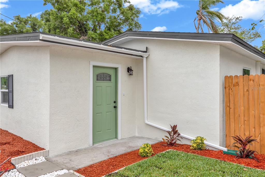 A light-colored house exterior features a green front door, a concrete walkway, and landscaping — 1262 SEMINOLA BOULEVARD, CASSELBERRY, FL