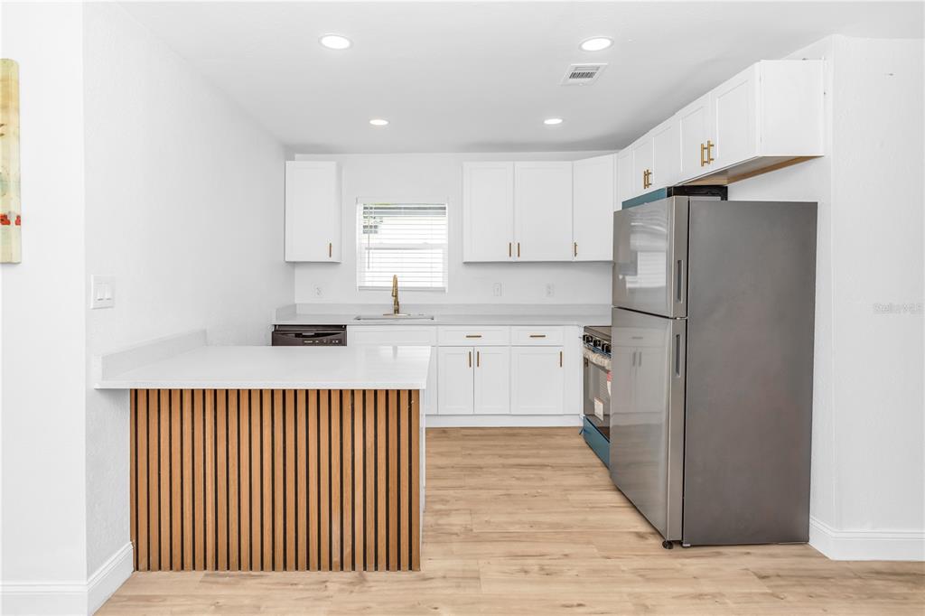A kitchen with white cabinets, stainless steel appliances, and a wood-slatted kitchen island — 1262 SEMINOLA BOULEVARD, CASSELBERRY, FL