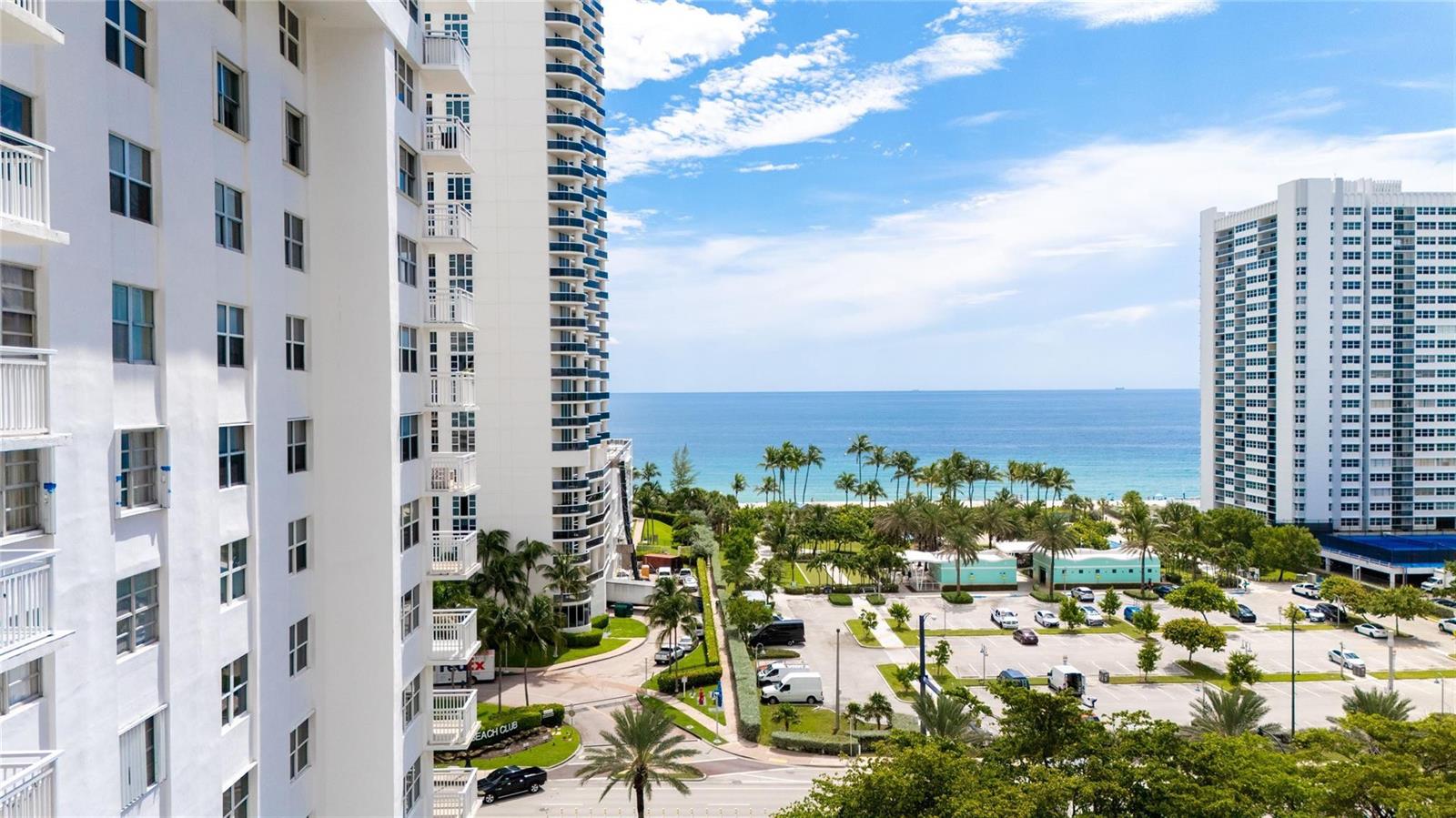 An elevated view shows two tall white apartment buildings overlooking a parking lot and beach — 1849 S Ocean Drive # 711, Hallandale Beach FL 33009, HALLANDALE BEACH, FL