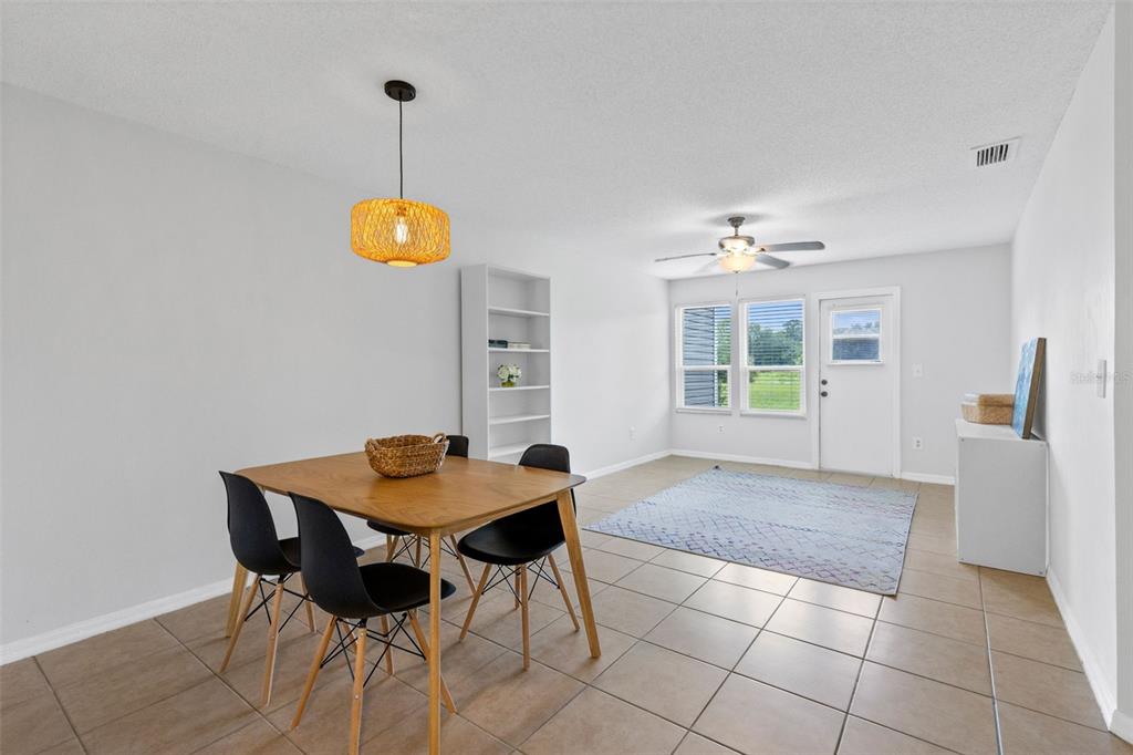 A dining area with a wooden table and black chairs sits beside a living space — 9514 DARIEN AVENUE UNIT 9514, ORLANDO, FL