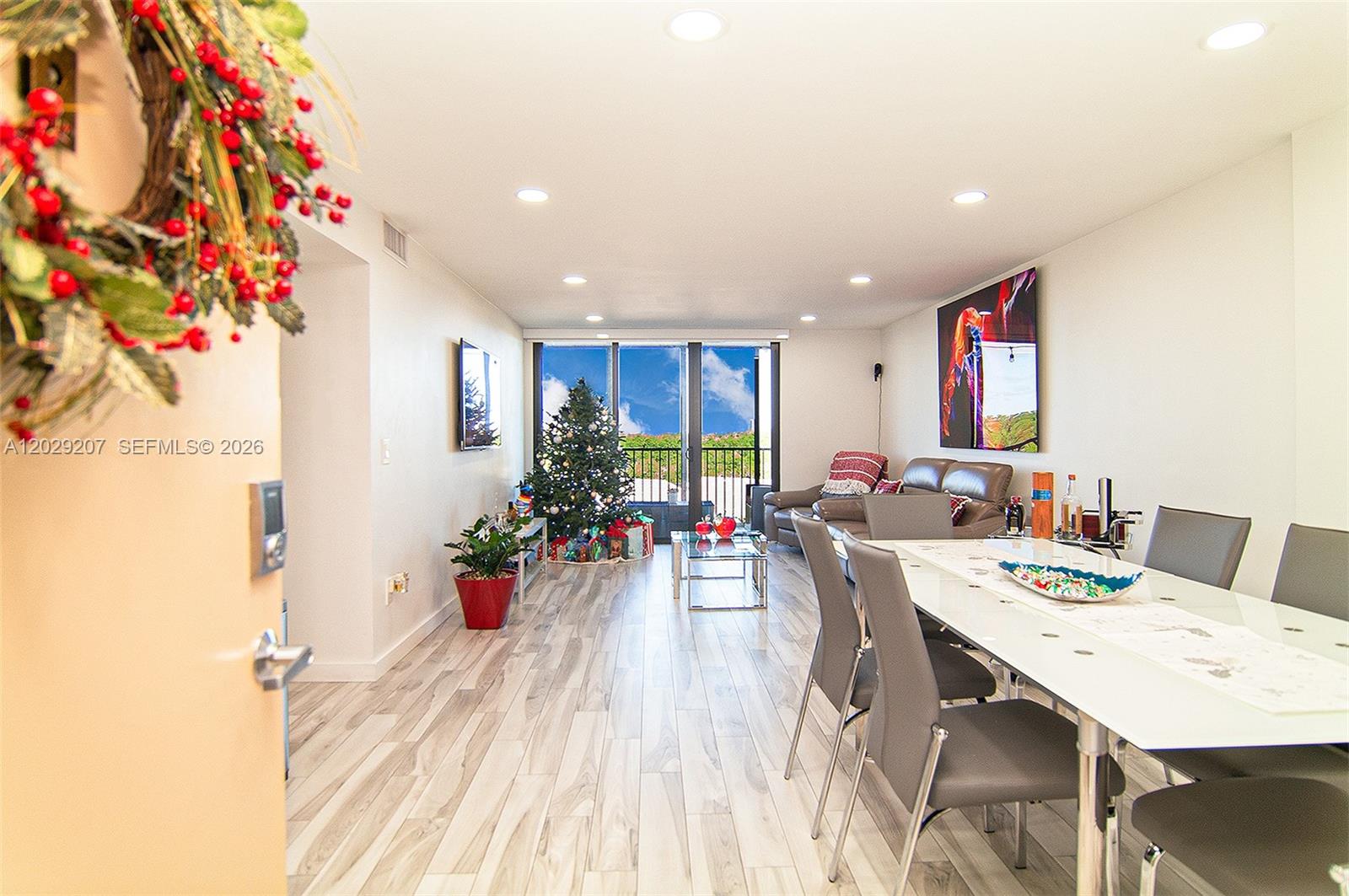 A bright living and dining area features light wood-look flooring and a Christmas tree — 2500 NE 135th St # B508, North Miami FL 33181, NORTH MIAMI, FL