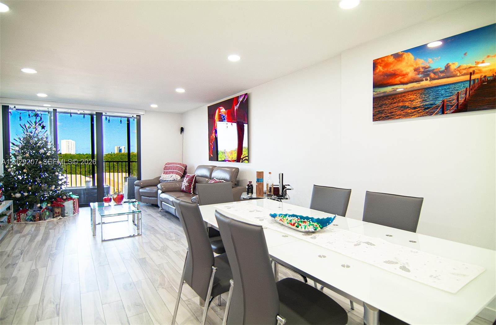 A living and dining area features light wood floors, a Christmas tree, and modern furniture — 2500 NE 135th St # B508, North Miami FL 33181, NORTH MIAMI, FL