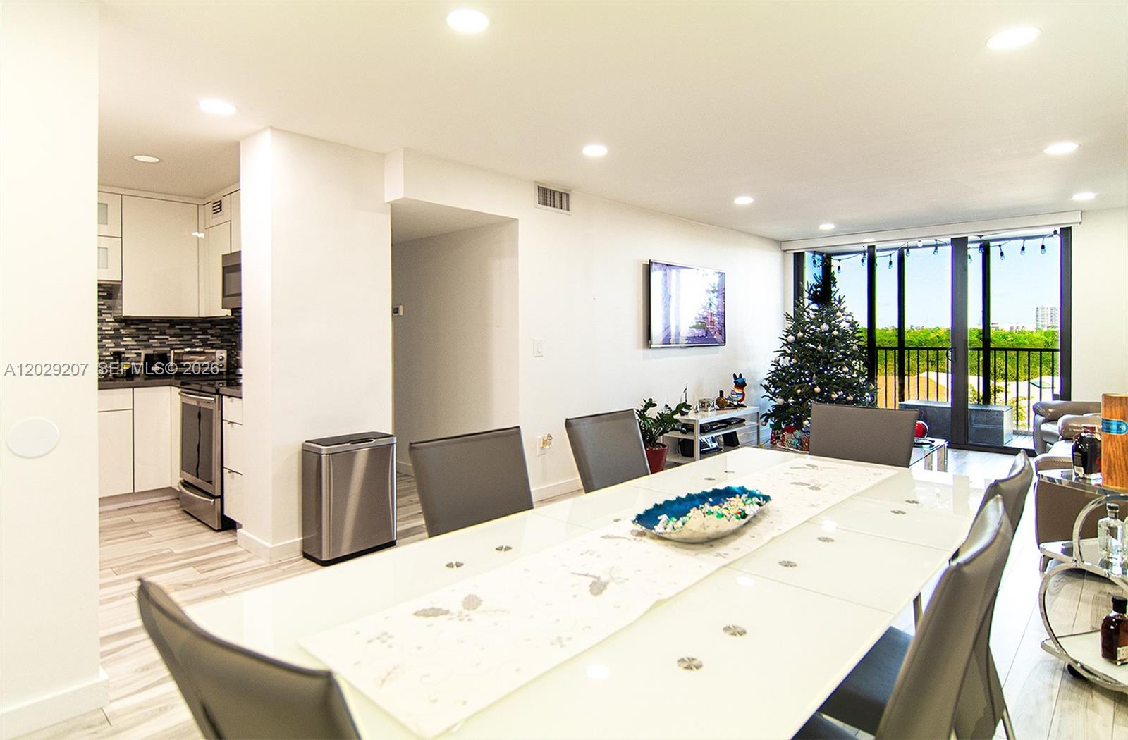 A dining area with a white table and chairs sits adjacent to a modern kitchen — 2500 NE 135th St # B508, North Miami FL 33181, NORTH MIAMI, FL