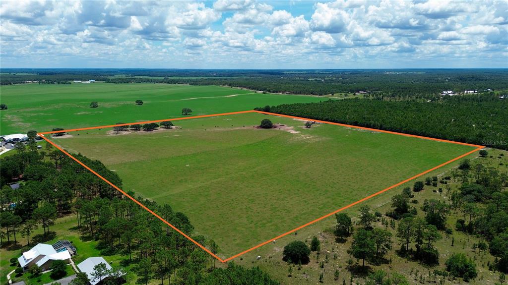 An aerial view shows a large, rectangular grassy field outlined in orange — SE 54TH STREET, MORRISTON, FL