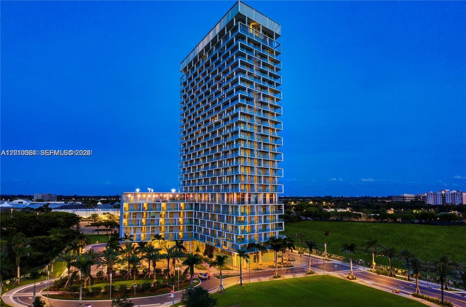 A tall, modern residential high-rise building stands against a clear blue twilight sky — 2000 Metropica Way # 2304, Sunrise FL 33323, SUNRISE, FL