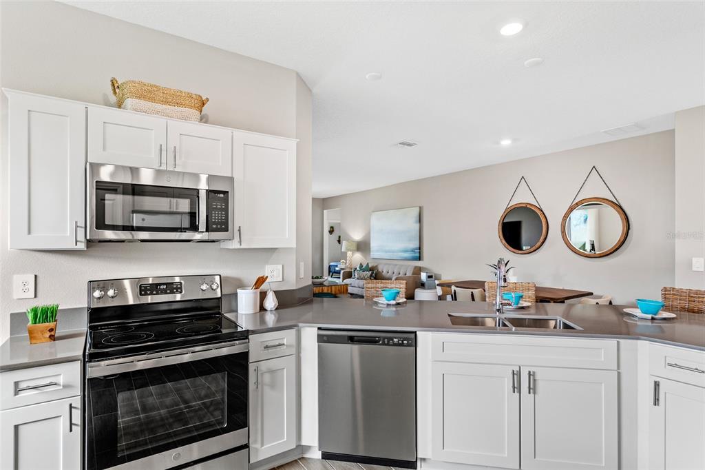 A modern kitchen features white cabinetry, stainless steel appliances, and a gray countertop — 5542 FIONA LANE, ST CLOUD, FL