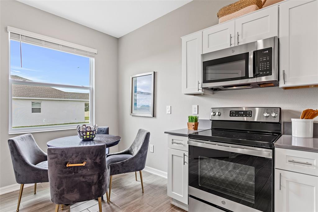 A kitchen dining area features white cabinets, stainless steel appliances, and a small round table — 5542 FIONA LANE, ST CLOUD, FL
