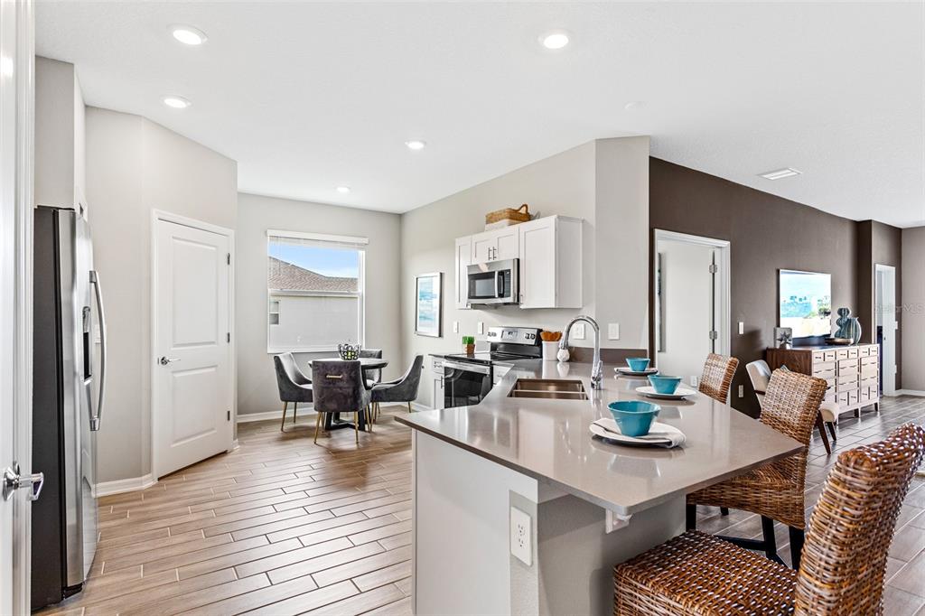 A kitchen with a quartz island, stainless steel appliances, and an adjacent dining area — 5542 FIONA LANE, ST CLOUD, FL
