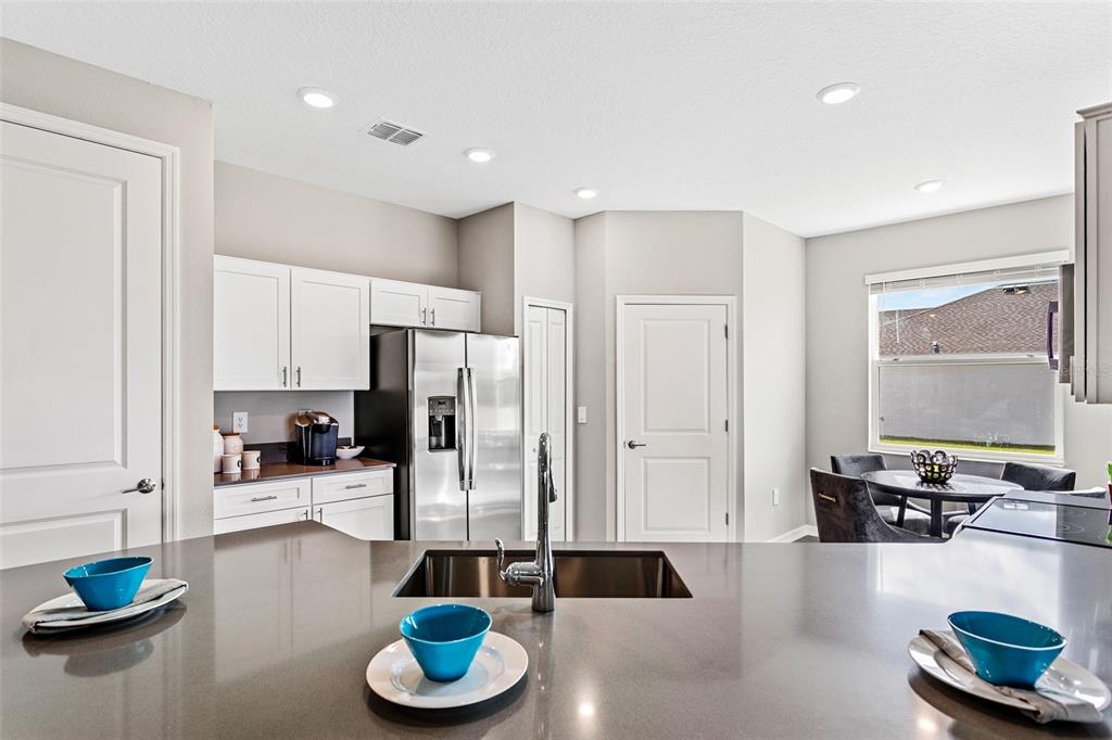 A kitchen features a dark countertop island with a sink, white cabinets, and stainless appliances — 5542 FIONA LANE, ST CLOUD, FL
