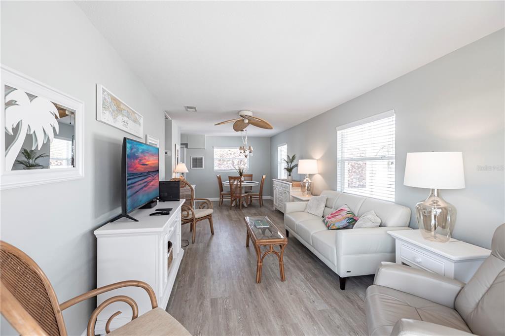 A living room and dining area feature light wood-look flooring, white furniture, and coastal decor — 6020 MIDNIGHT PASS ROAD UNIT 10, SARASOTA, FL