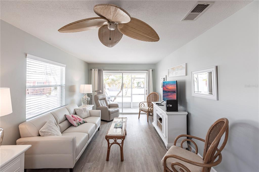 A living room features a white sofa, rattan chairs, a ceiling fan, and sliding glass doors — 6020 MIDNIGHT PASS ROAD UNIT 10, SARASOTA, FL