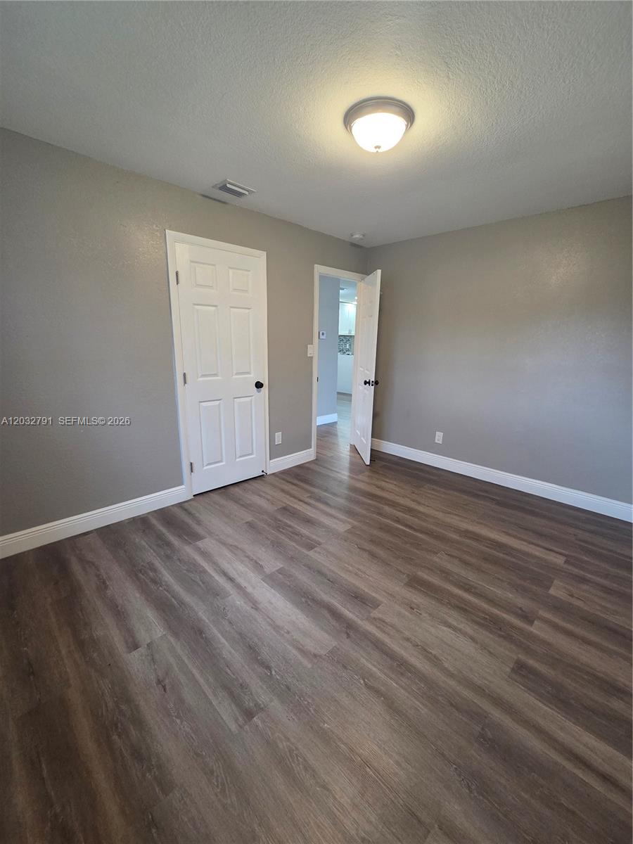 A room with gray walls, wood-look flooring, a ceiling light, and two white doors — 2350 NW 12th Ct # 0, Pompano Beach FL 33069, POMPANO BEACH, FL
