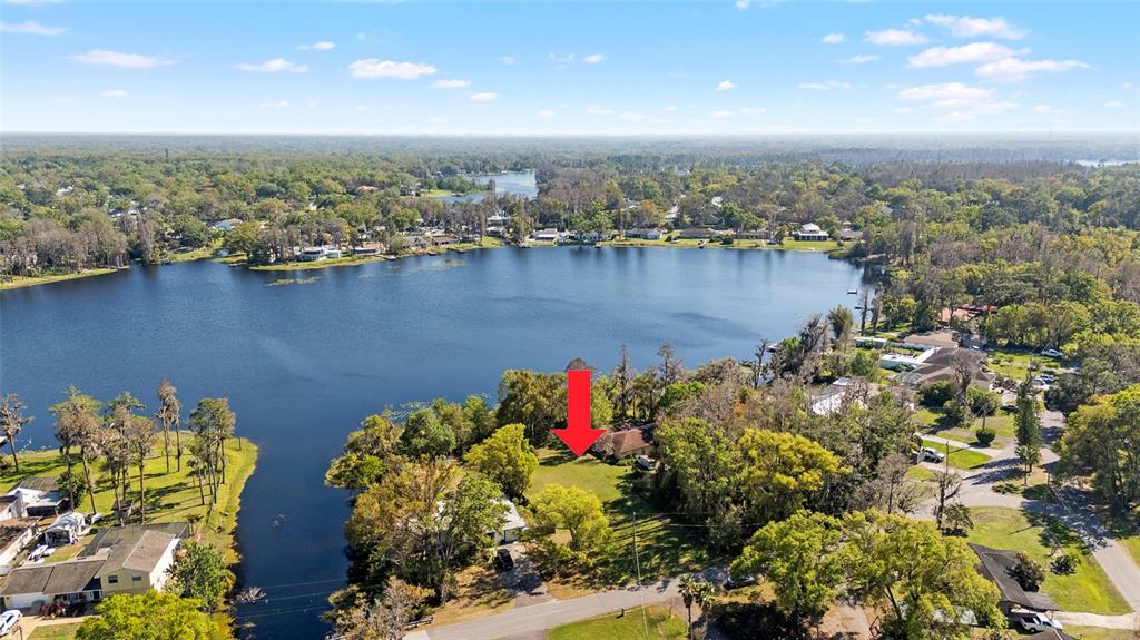 An aerial view shows a residential lot with a house situated near a lake — 18703.5 LAKESHORE DR, LUTZ, FL