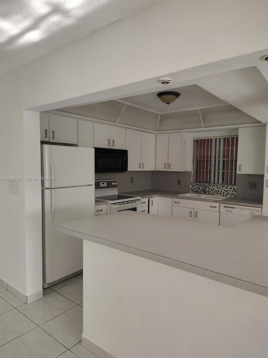 A kitchen features white cabinets, a white refrigerator, a stove, and a breakfast bar — 200 NE 12th Ave # 1C, Hallandale Beach FL 33009, HALLANDALE BEACH, FL