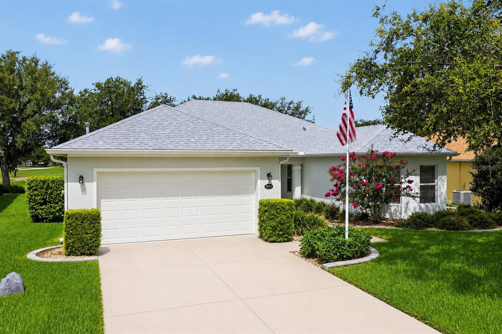 A concrete walkway leads to the covered front entrance of a house with landscaping — 26821 AUGUSTA SPRINGS CIRCLE, LEESBURG, FL