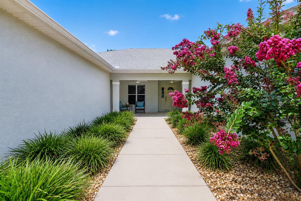 A covered patio features two ceiling fans, wicker chairs with blue cushions, and a white door — 26821 AUGUSTA SPRINGS CIRCLE, LEESBURG, FL
