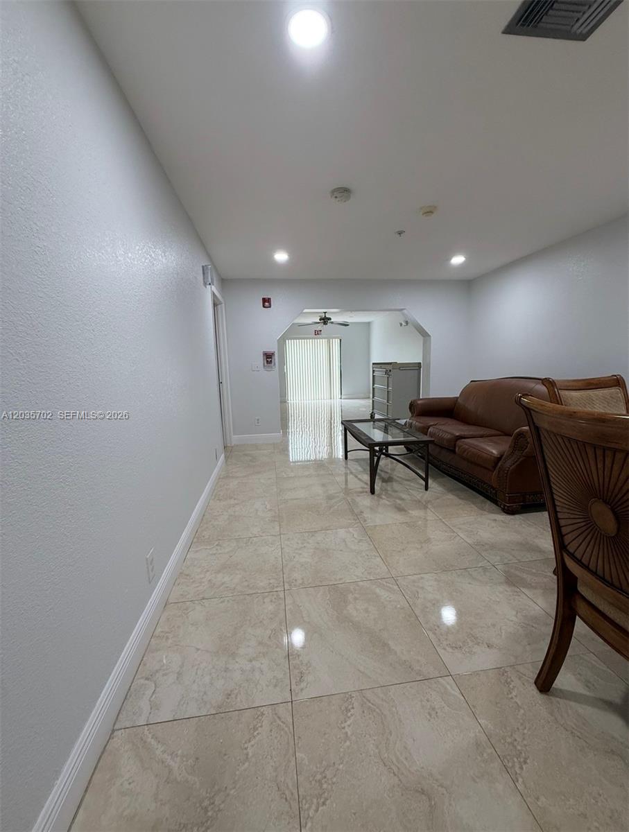 A living area features light-colored tile flooring, a brown leather sofa, and a glass coffee table — CORAL SPRINGS, FL