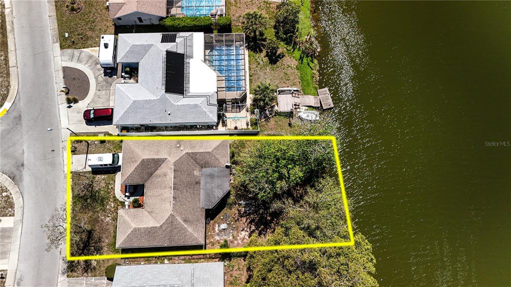 An aerial view shows a single-story house with a large tree beside a lake — 7619 VIENNA LANE, PORT RICHEY, FL