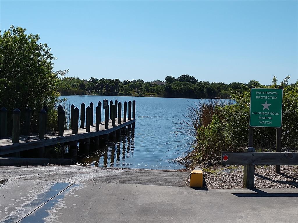 A concrete boat ramp leads to a wooden dock on a calm lake — 14473 EDNA CIRCLE, PORT CHARLOTTE, FL