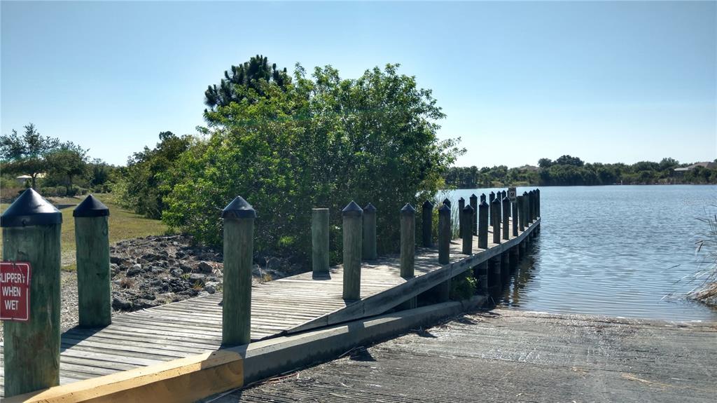 A wooden boat dock extends into a lake next to a concrete boat ramp — 14473 EDNA CIRCLE, PORT CHARLOTTE, FL