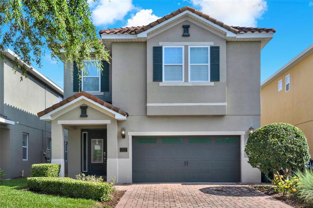 A two-story suburban house with a gray stucco exterior, a tiled roof, and a garage — 7613 BROOKHURST LANE, KISSIMMEE, FL